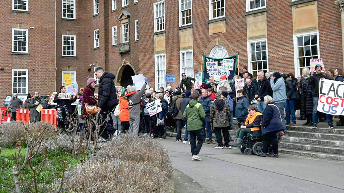 A group of people gathered outside a building, holding placards and protesting.